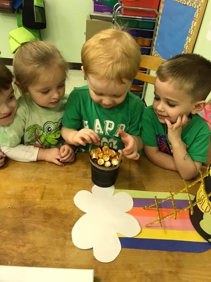 Three children at a table playing with a pot of gold coins