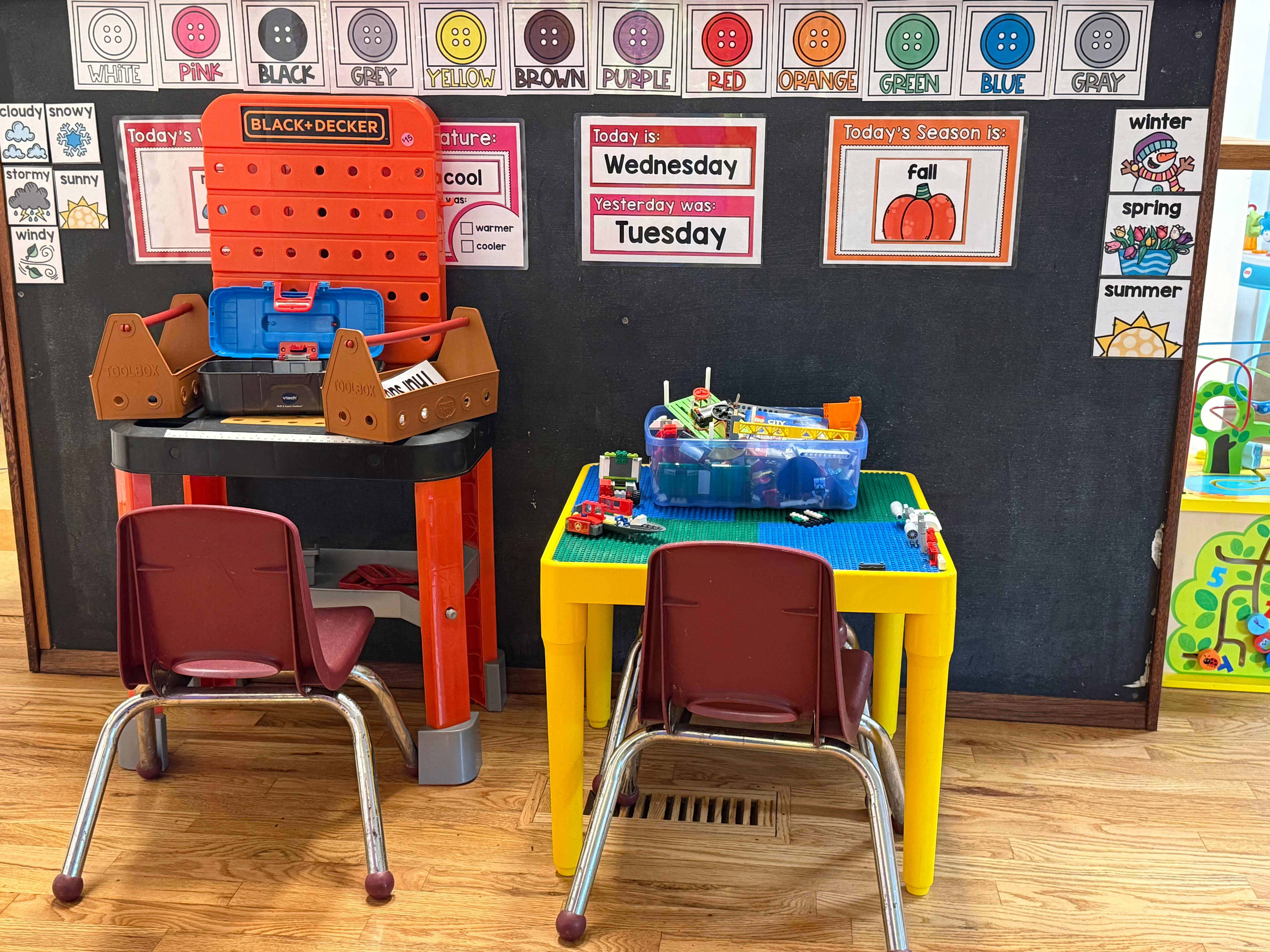 Children's classroom with a toy workbench, LEGO table, and learning charts