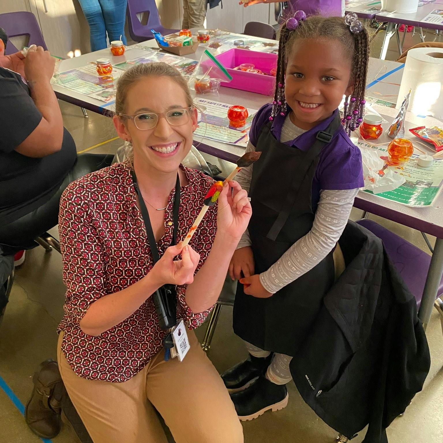 Person and child holding a craft stick