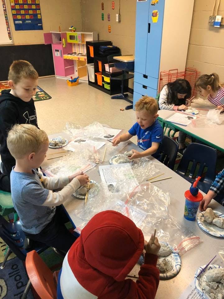 Children sitting at a table doing an activity with clay or dough