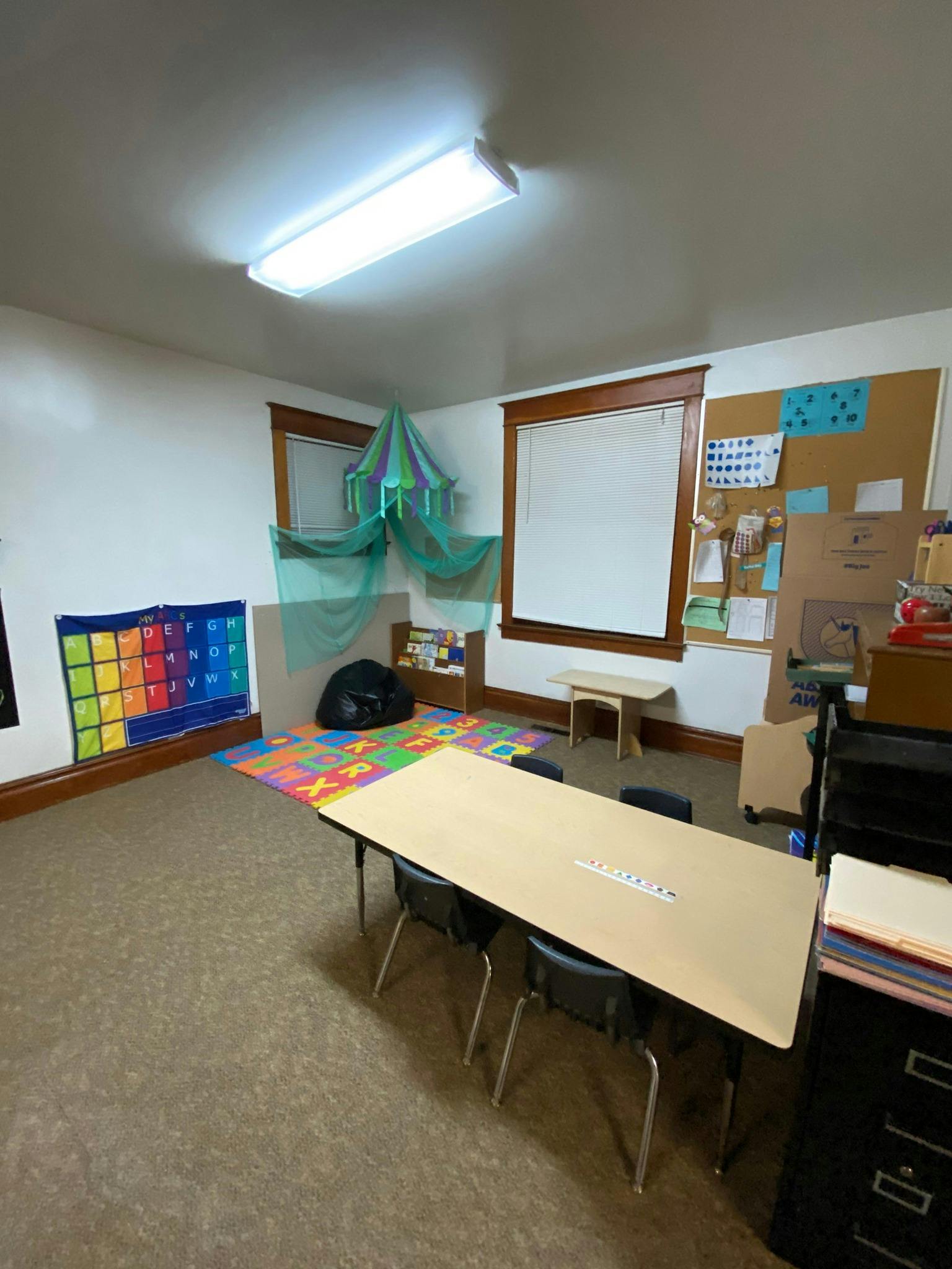Classroom with tables, chairs, and colorful alphabet chart