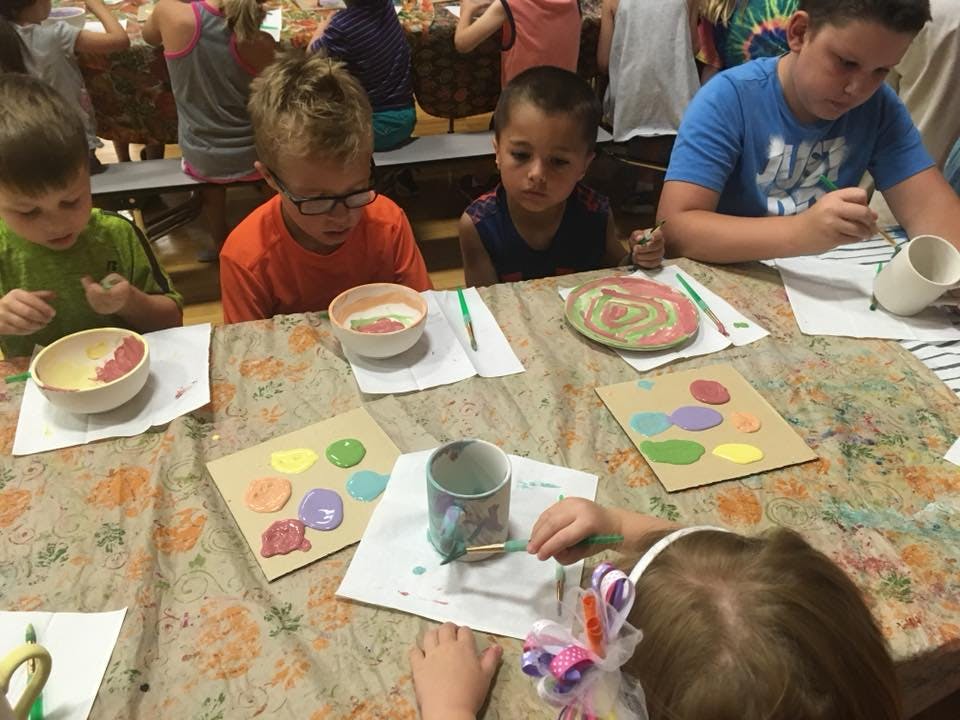 Children painting pottery at a table