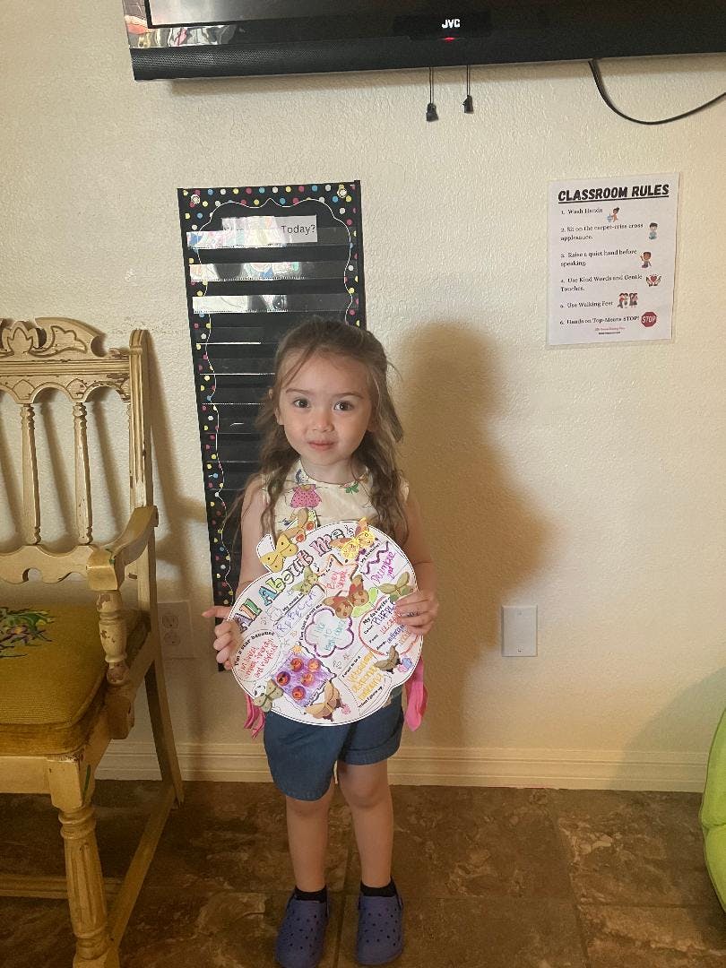 Child holding a decorated paper plate in a classroom