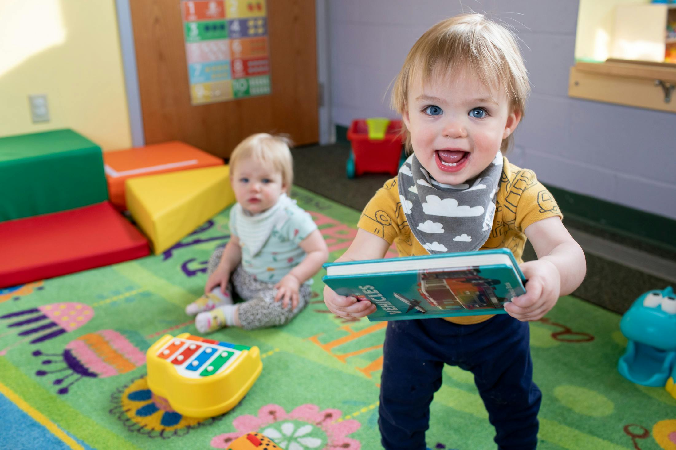 Two children playing on a rug in a classroom