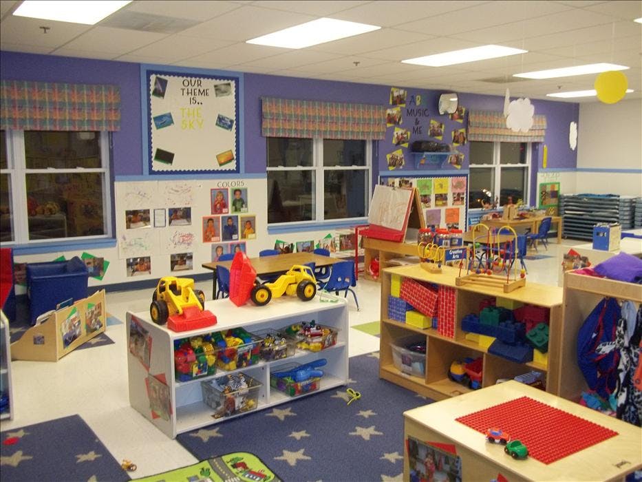 A classroom with toys, tables, chairs, and learning displays on the walls