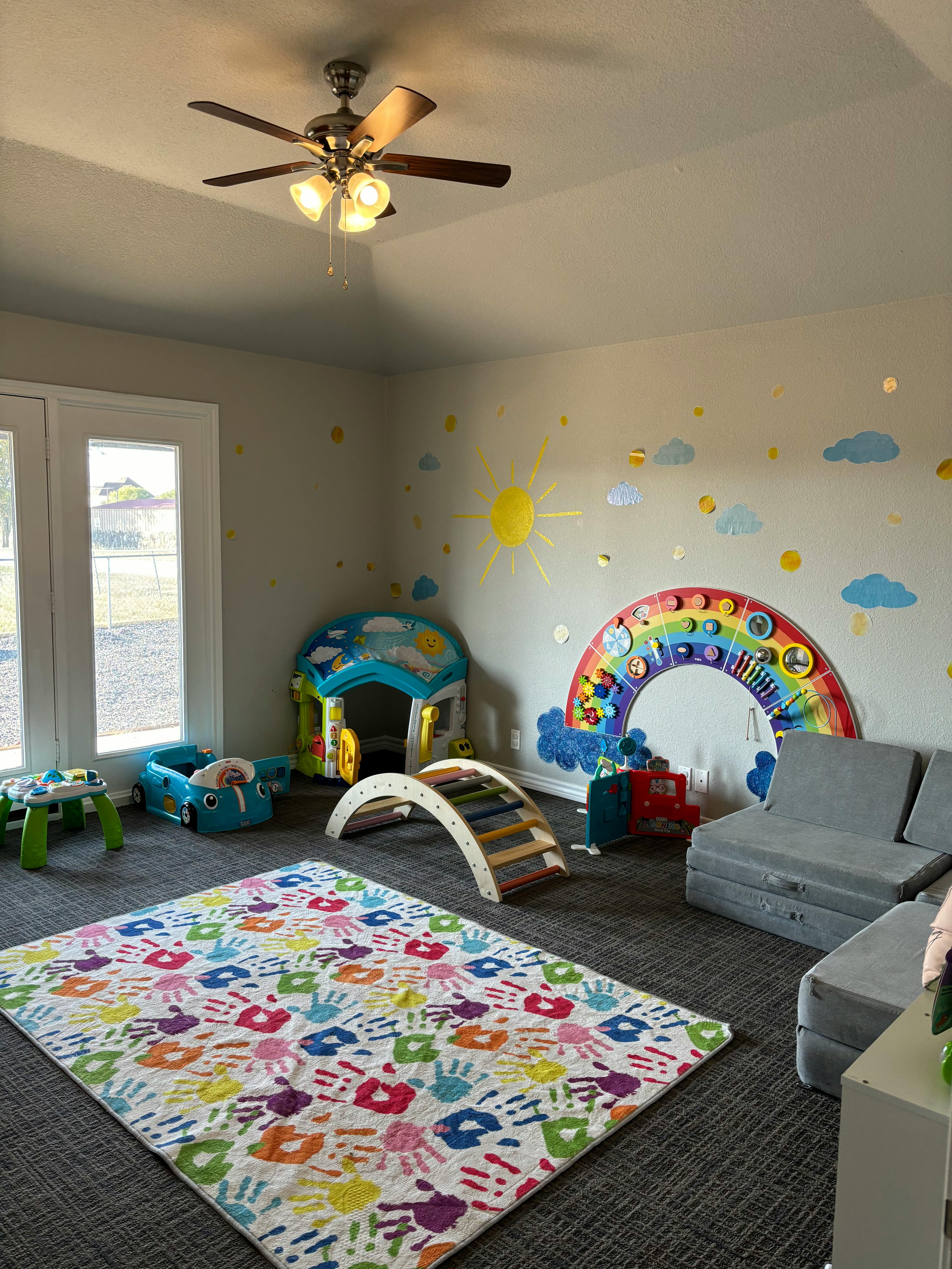 Playroom with a colorful rug, play structures, and wall decals