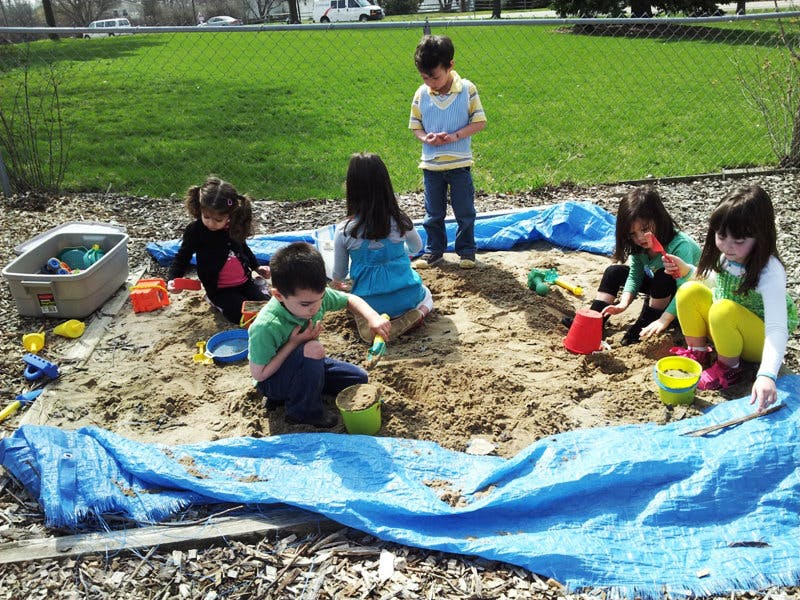 Children playing in a sandbox with toys