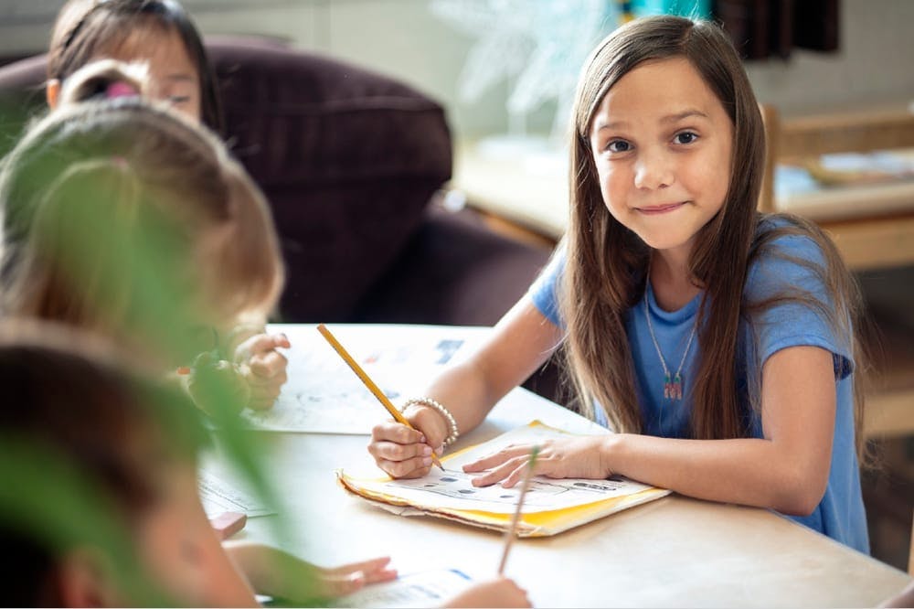 Child writing with a pencil at a table
