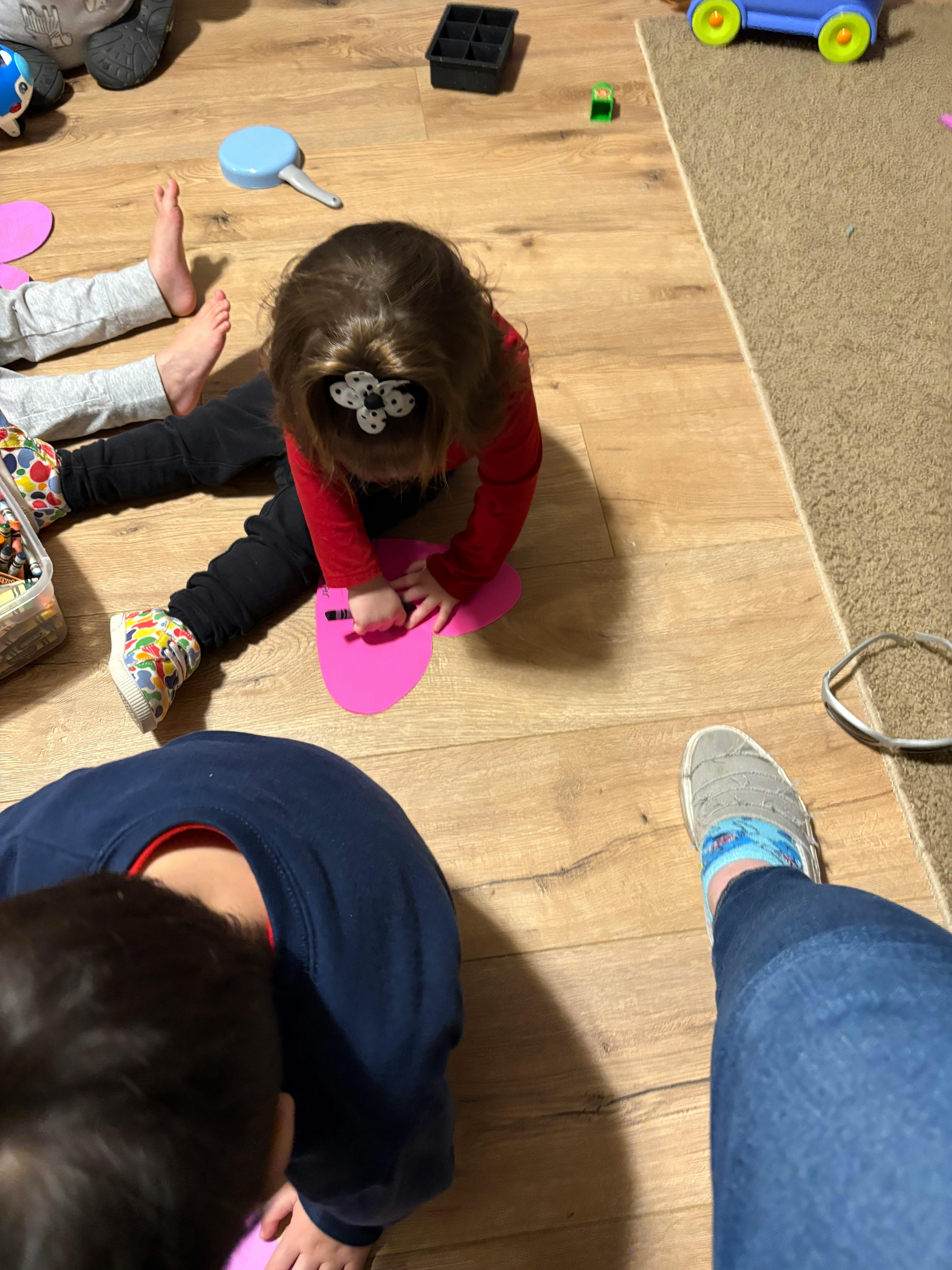 Child playing with a pink toy on a wooden floor