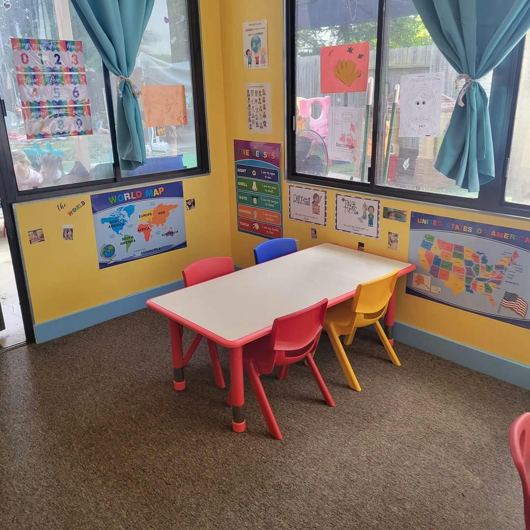 Classroom with small table and chairs, maps and charts on yellow walls