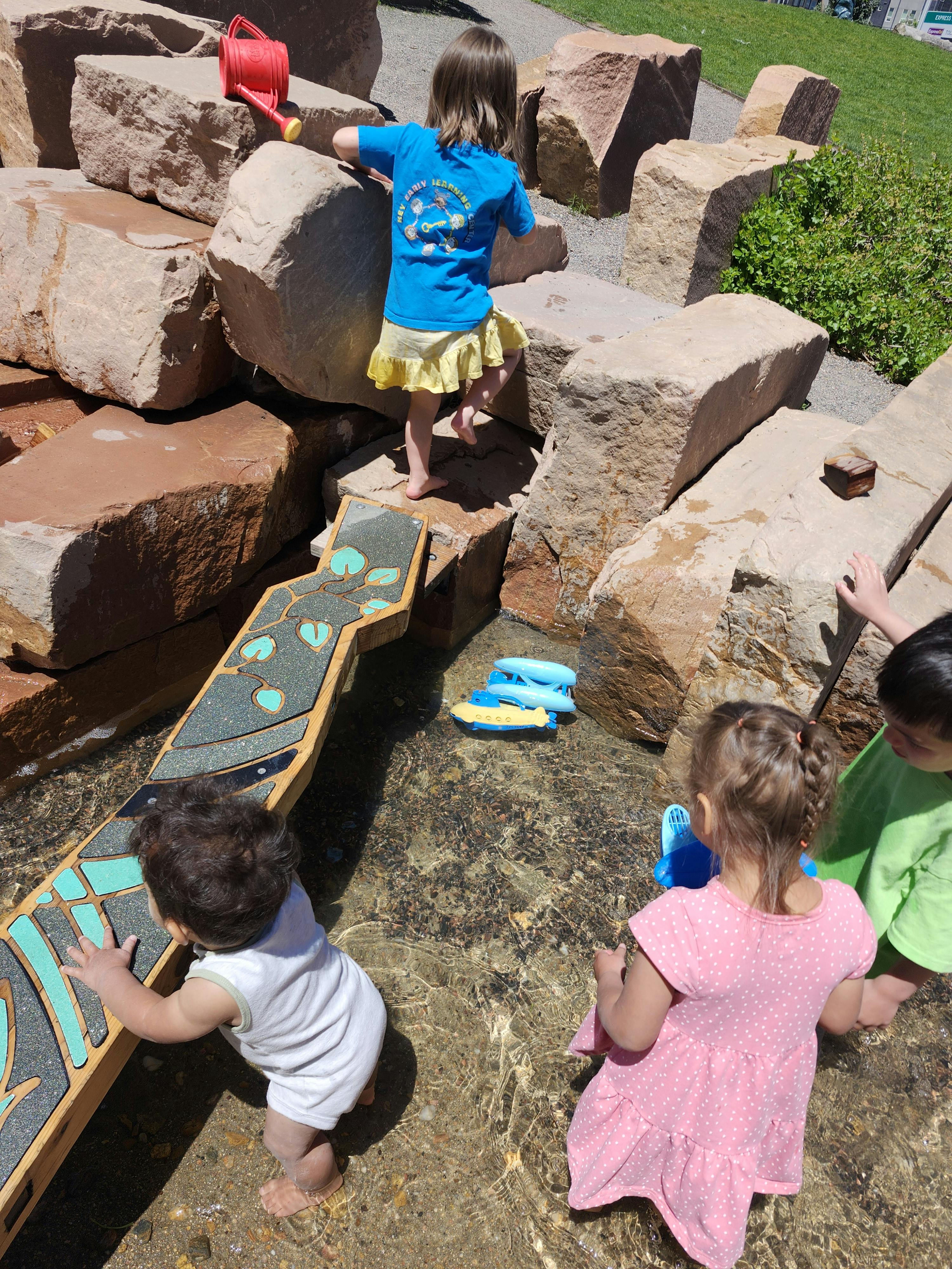Children playing in shallow water among rocks