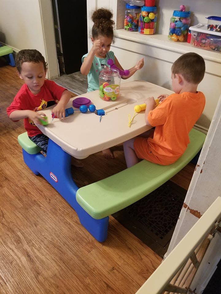 Three children playing with toys at a small table