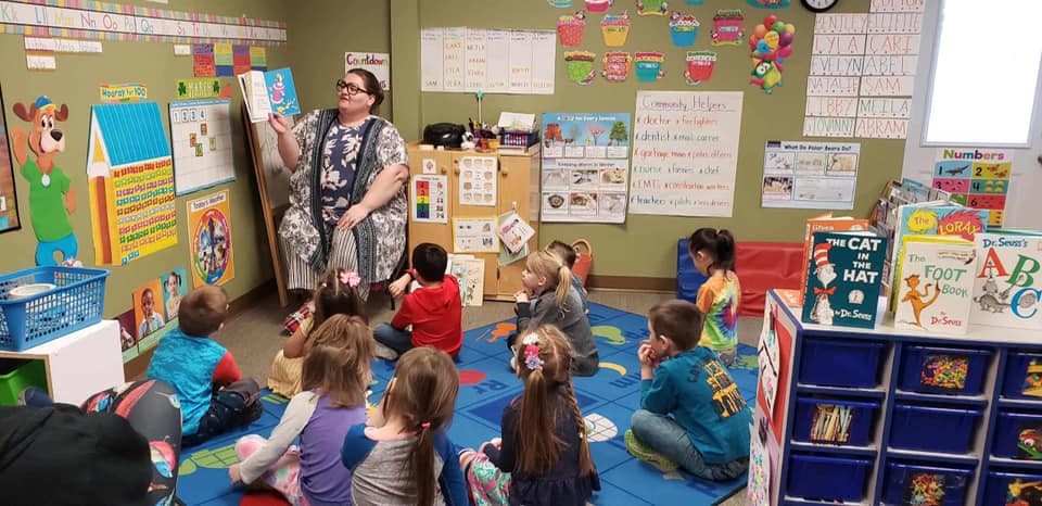 Adult reading a book to children in a classroom