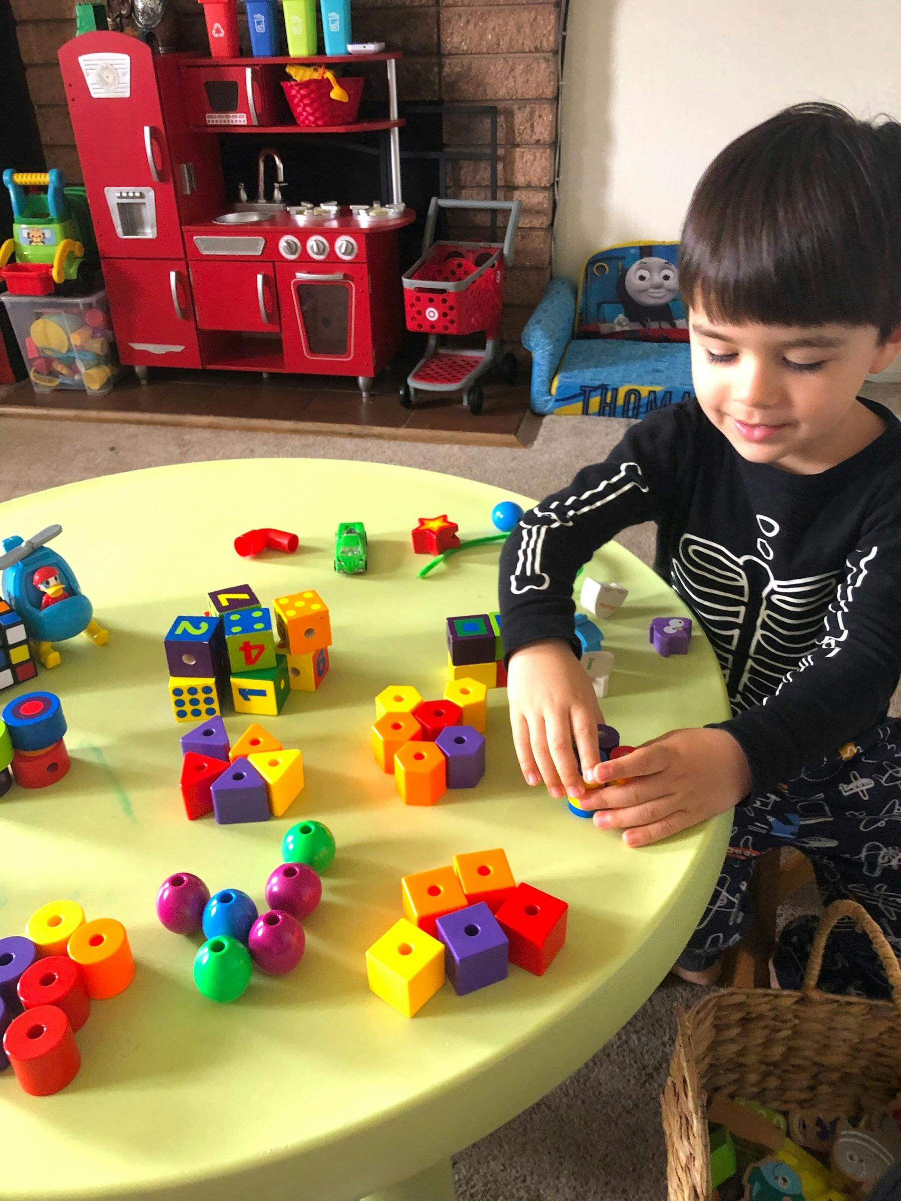 Child playing with colorful blocks and toys on a green table