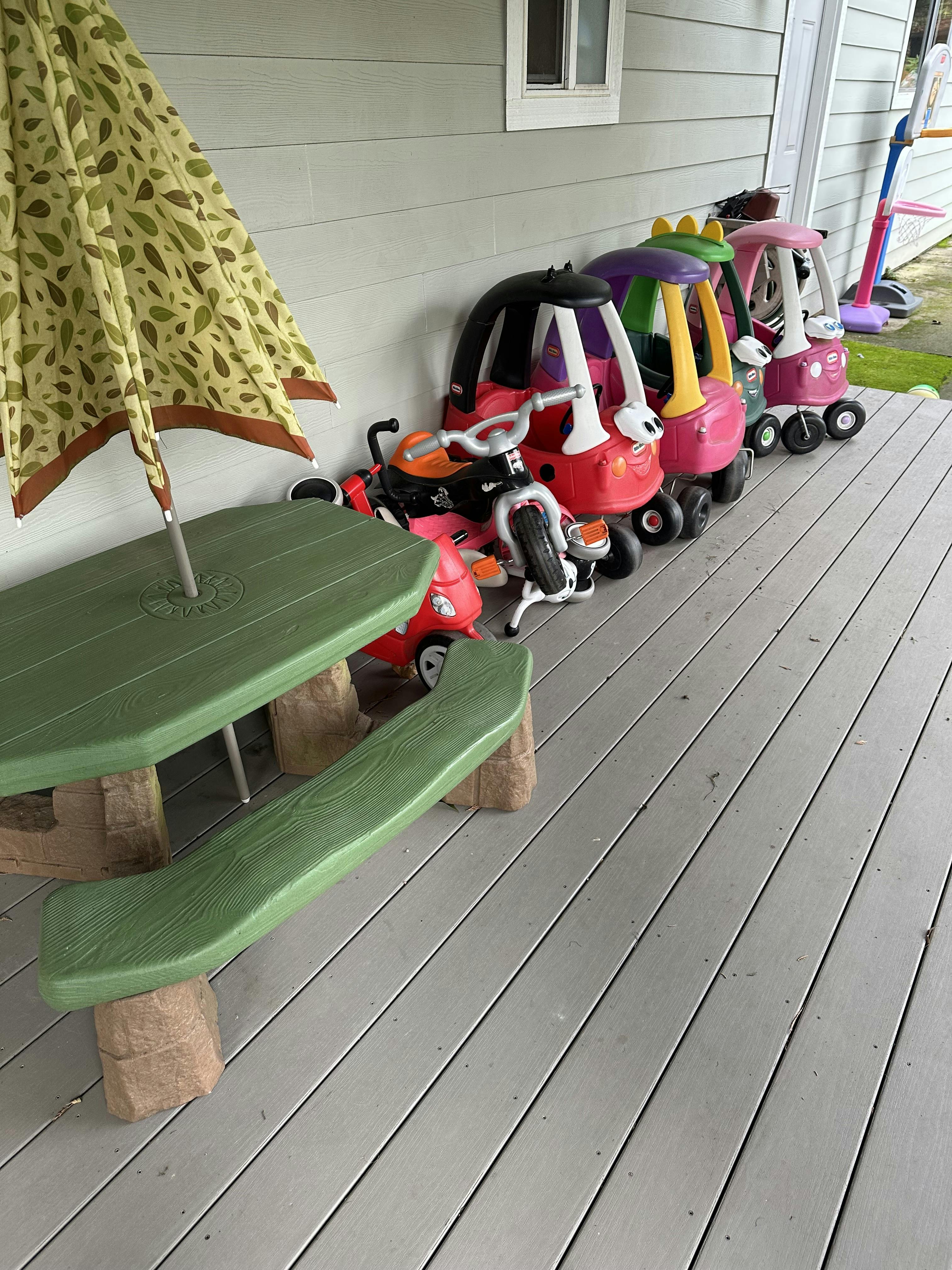 Children's picnic table with umbrella and ride-on toys on a deck