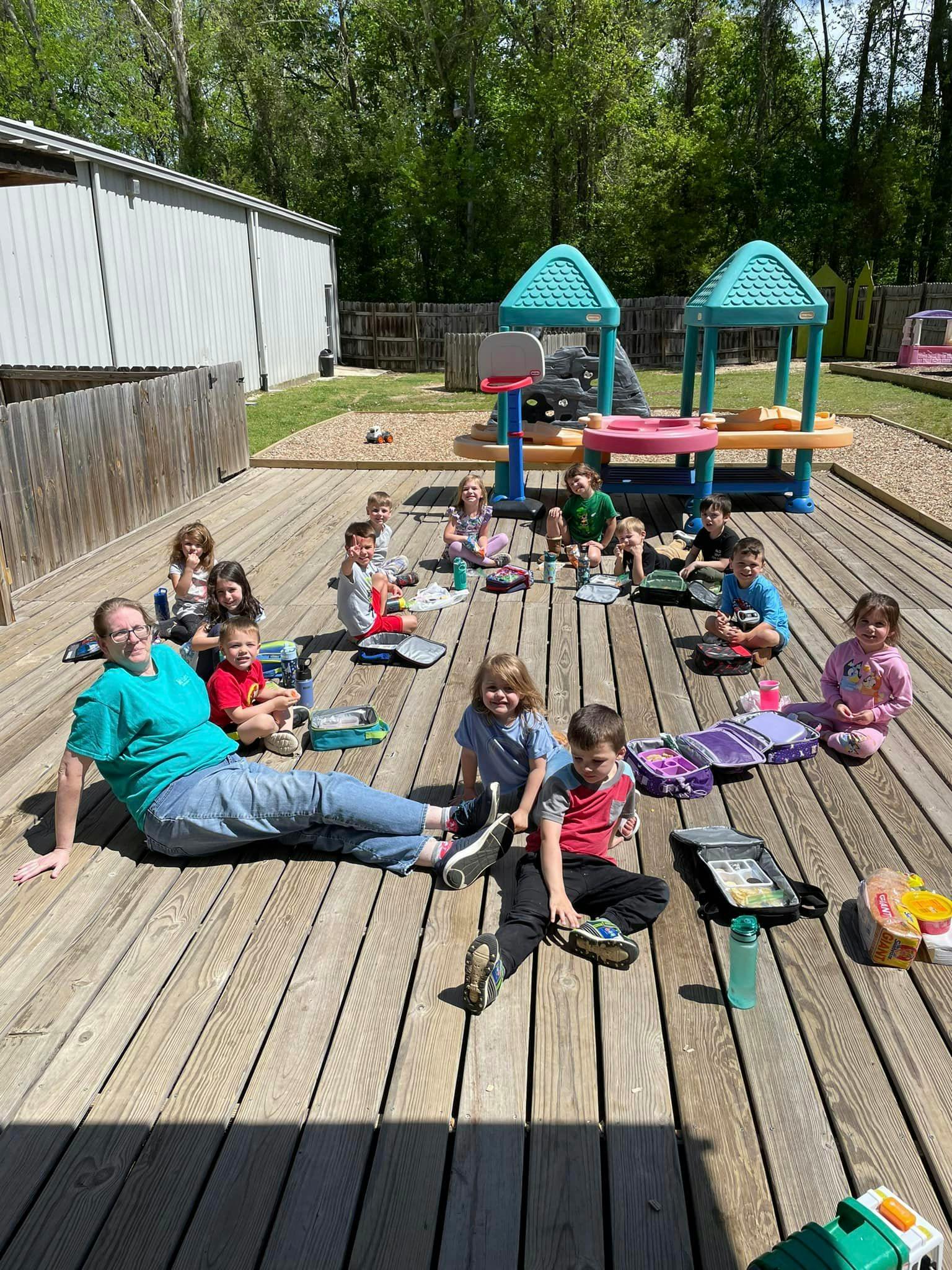 Adult and children sitting on a wooden deck outdoors