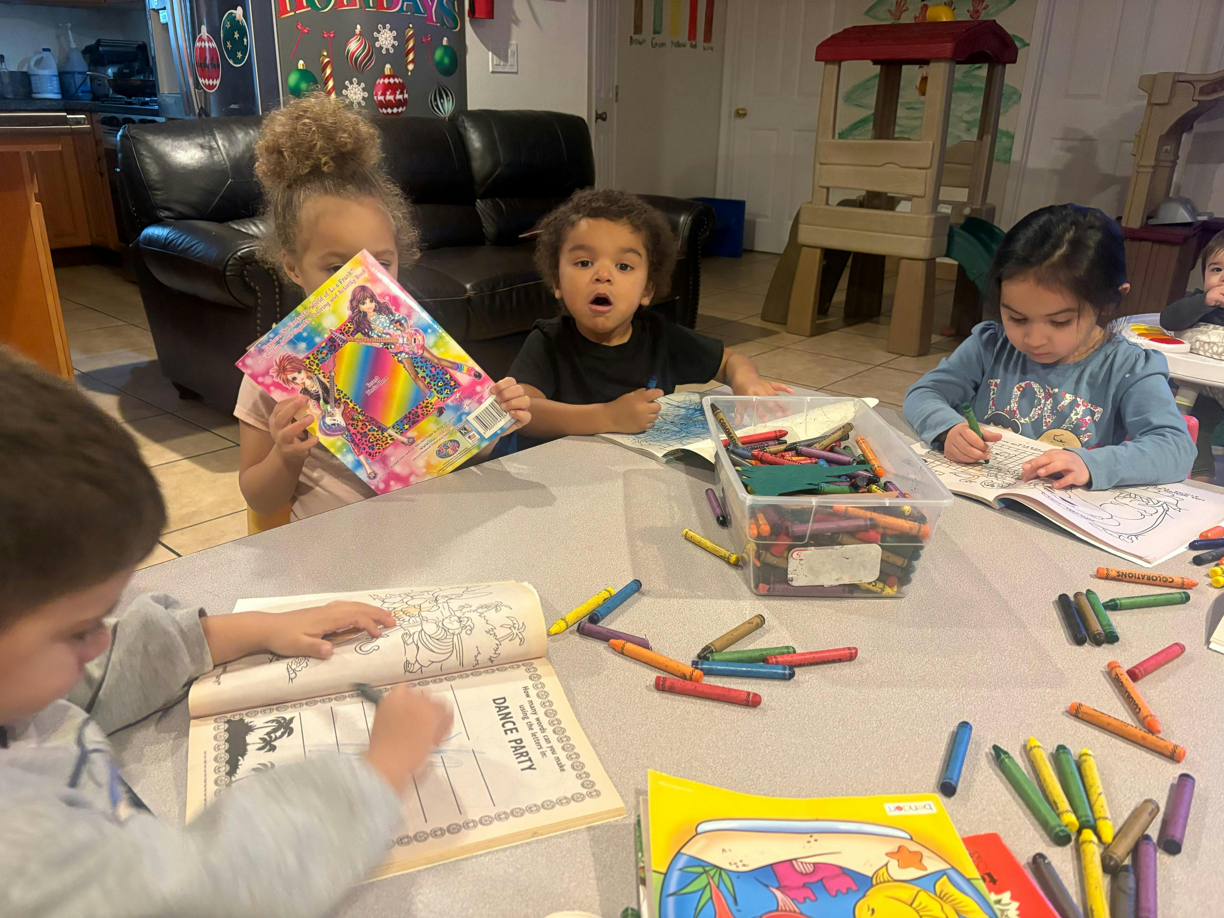Four children coloring at a table with crayons and coloring books