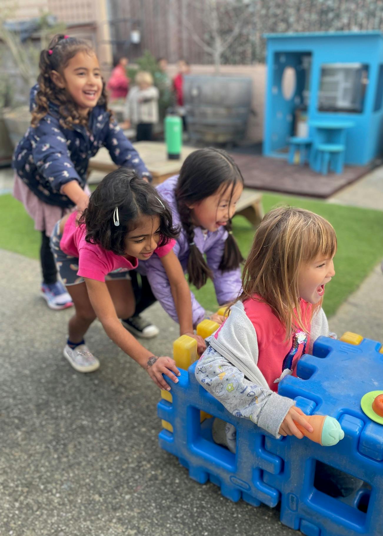 Four children playing with a blue toy outdoors
