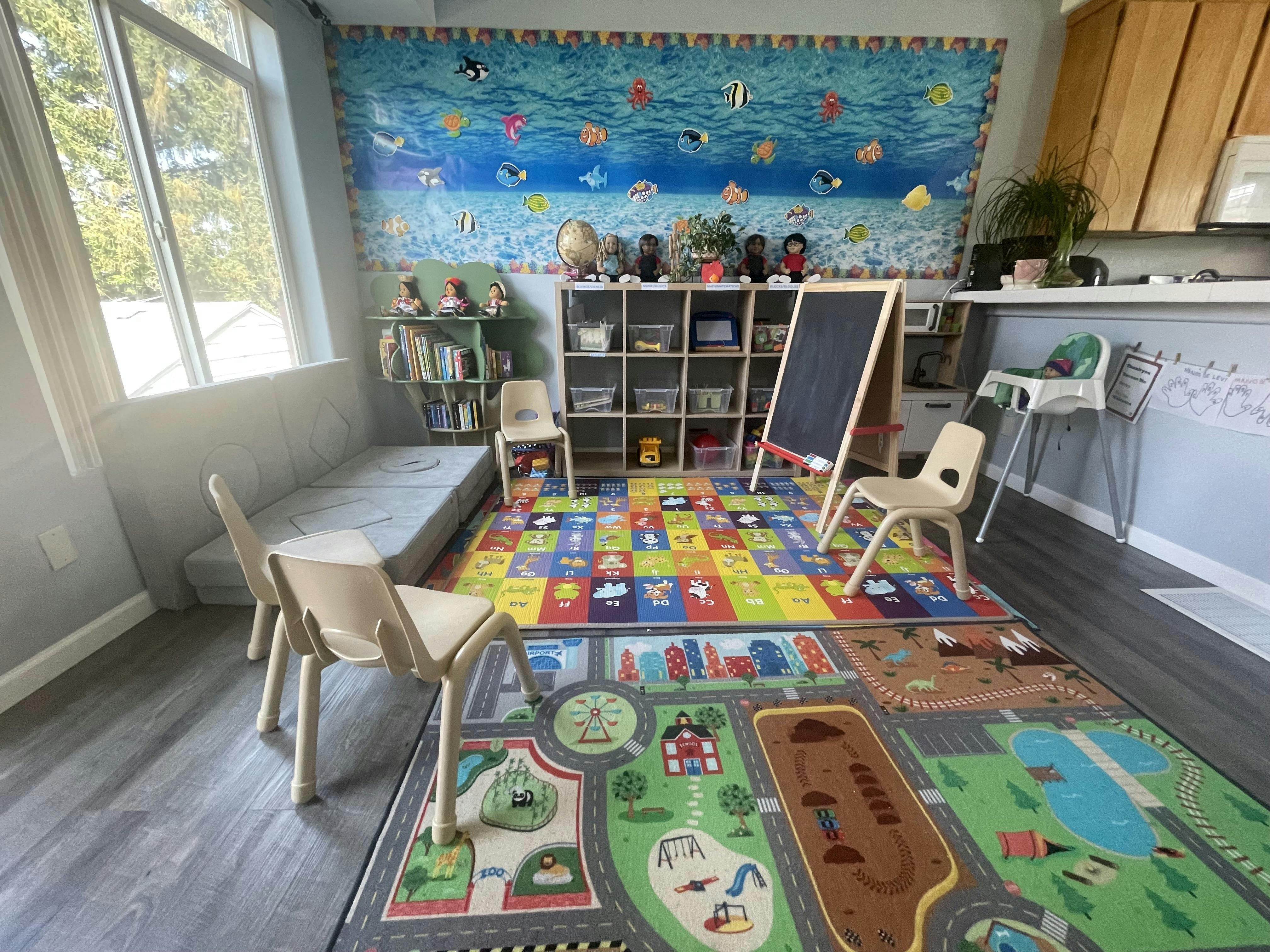 Playroom with colorful alphabet and road map rugs, small chairs, and an easel