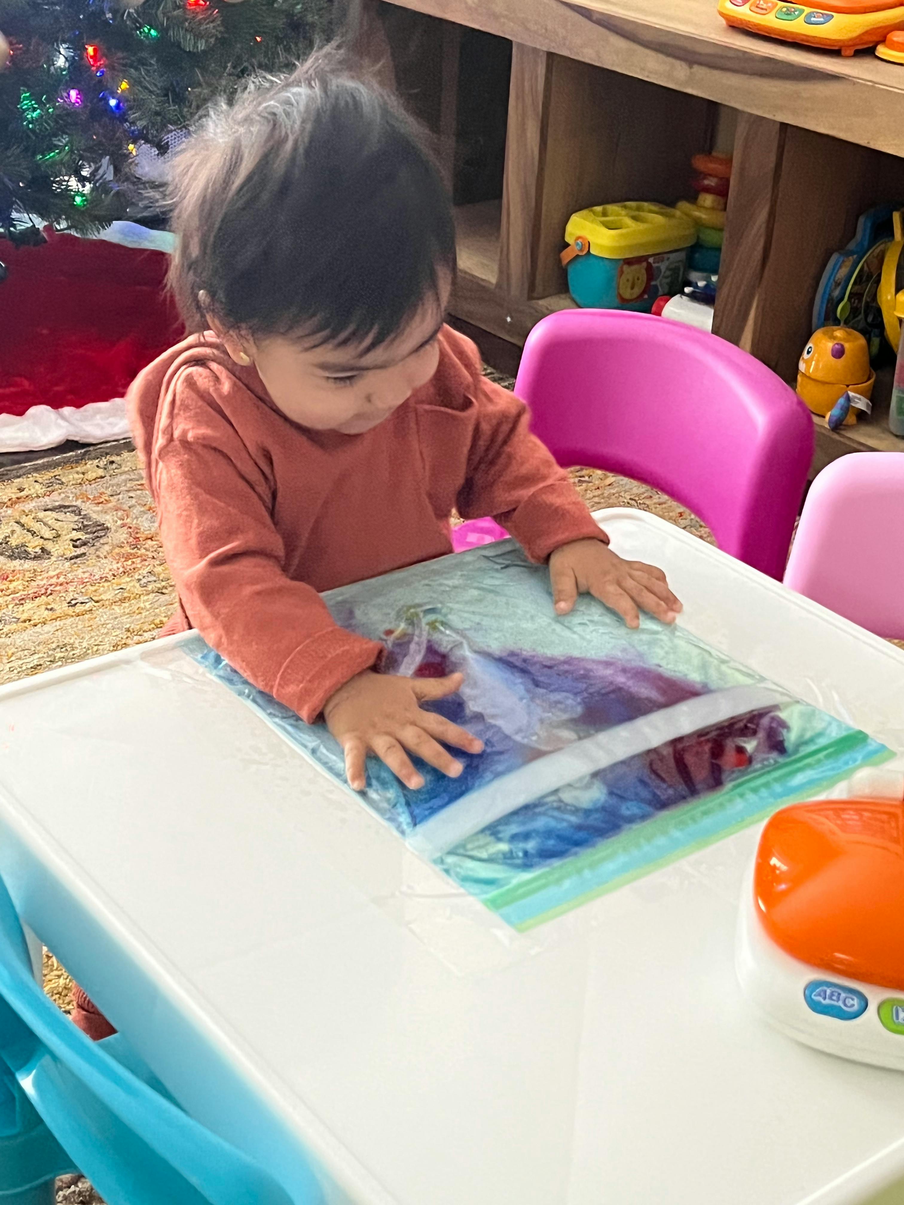 Child playing with a colorful sensory bag on a white table