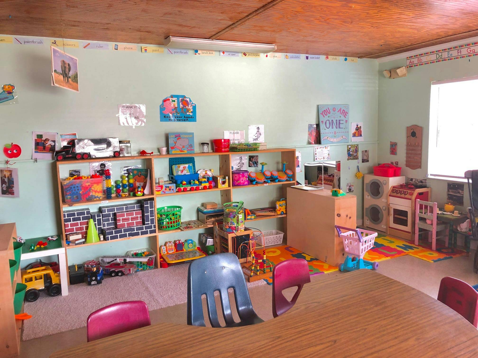 Classroom with shelves of toys, small chairs, and a table