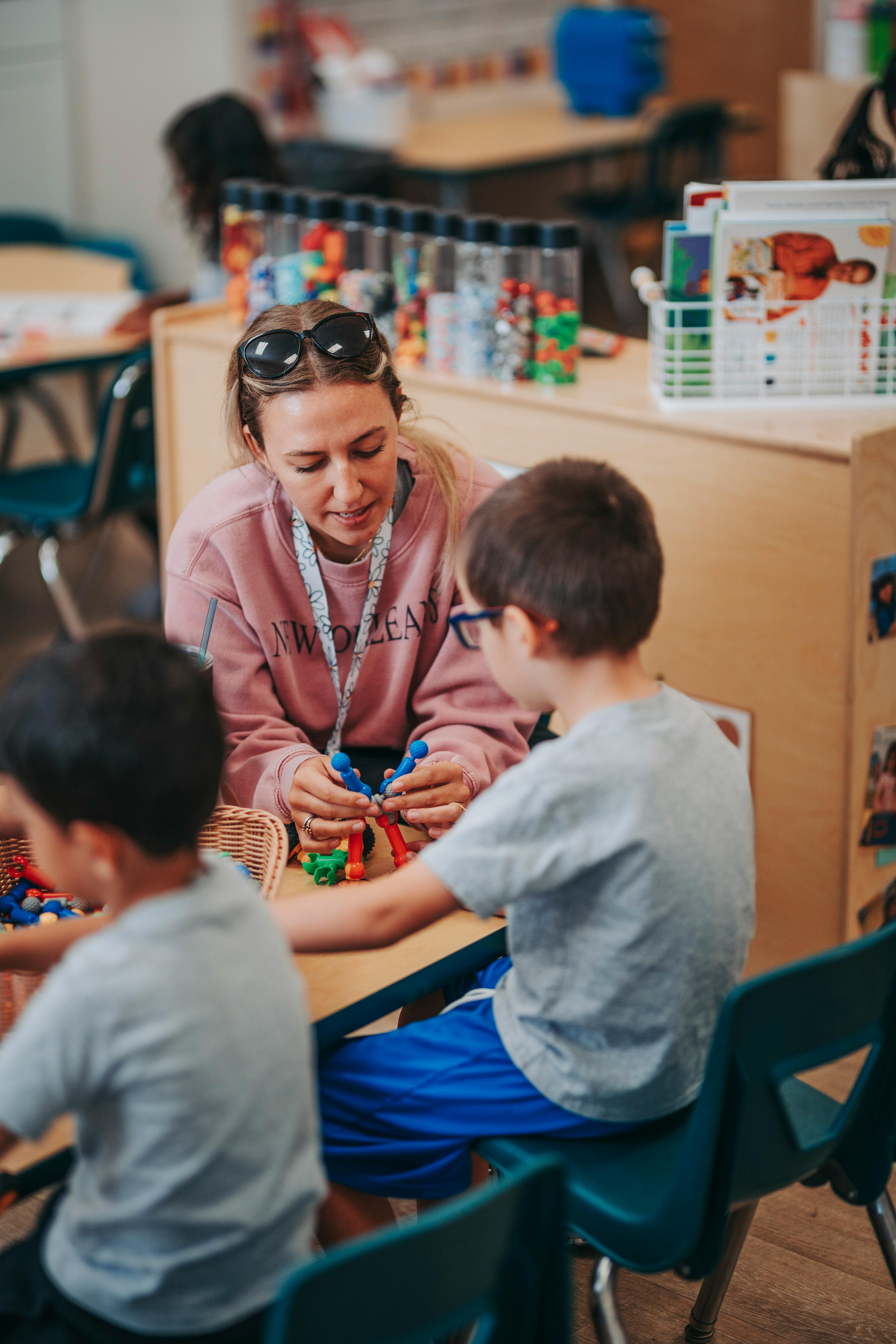 Adult and child playing with colorful building toys in a classroom