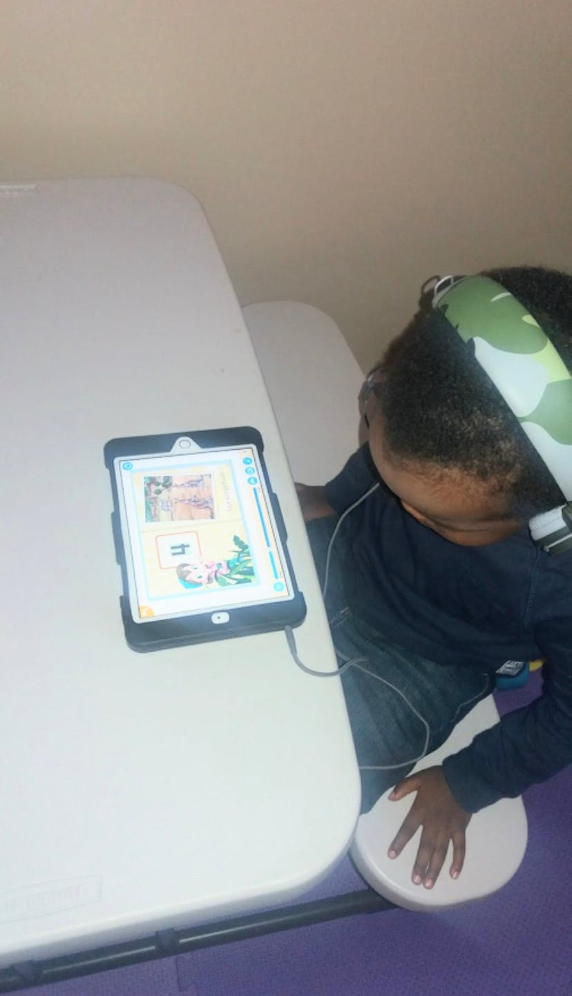 Child wearing headphones and looking at a tablet on a table