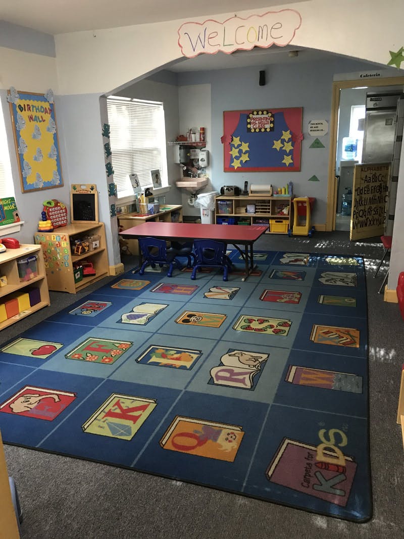 Classroom with a blue alphabet rug, red table, and chairs