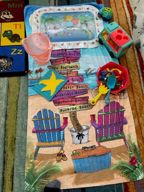 Beach-themed playmat with toys, including a water mat, bucket, and sand toys