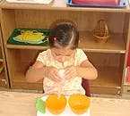 Child working with two orange objects on a table