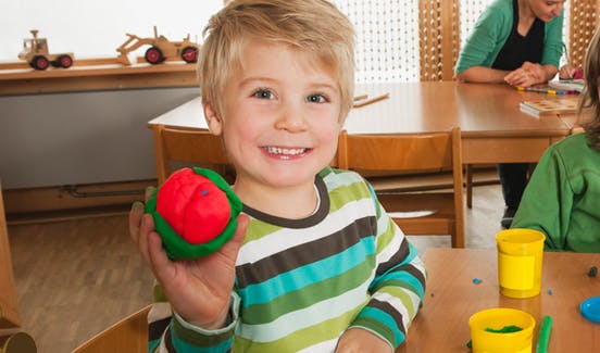 Child holding red and green playdough