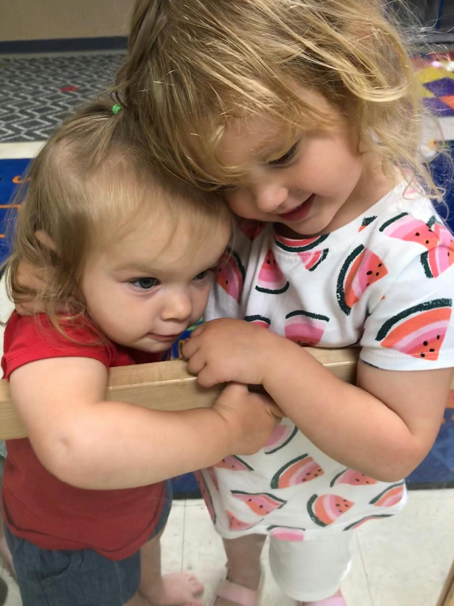 Two children embracing, one resting head on the other's shoulder
