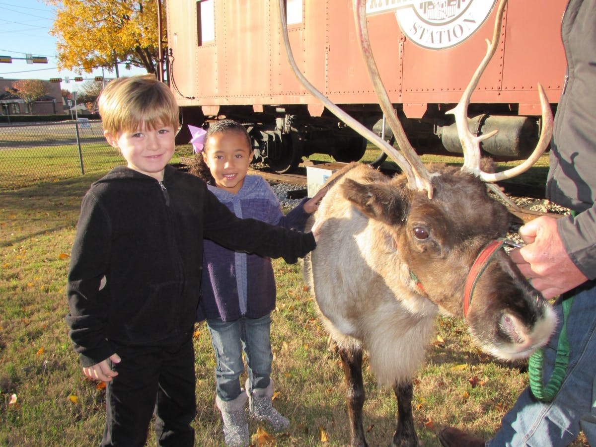 Two children petting a reindeer