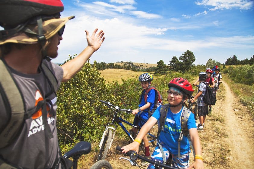 Person giving high five to children on bikes on a dirt path