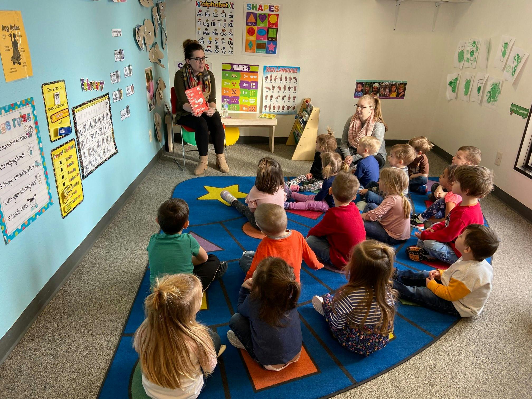 Adult reading to children sitting on a rug in a classroom