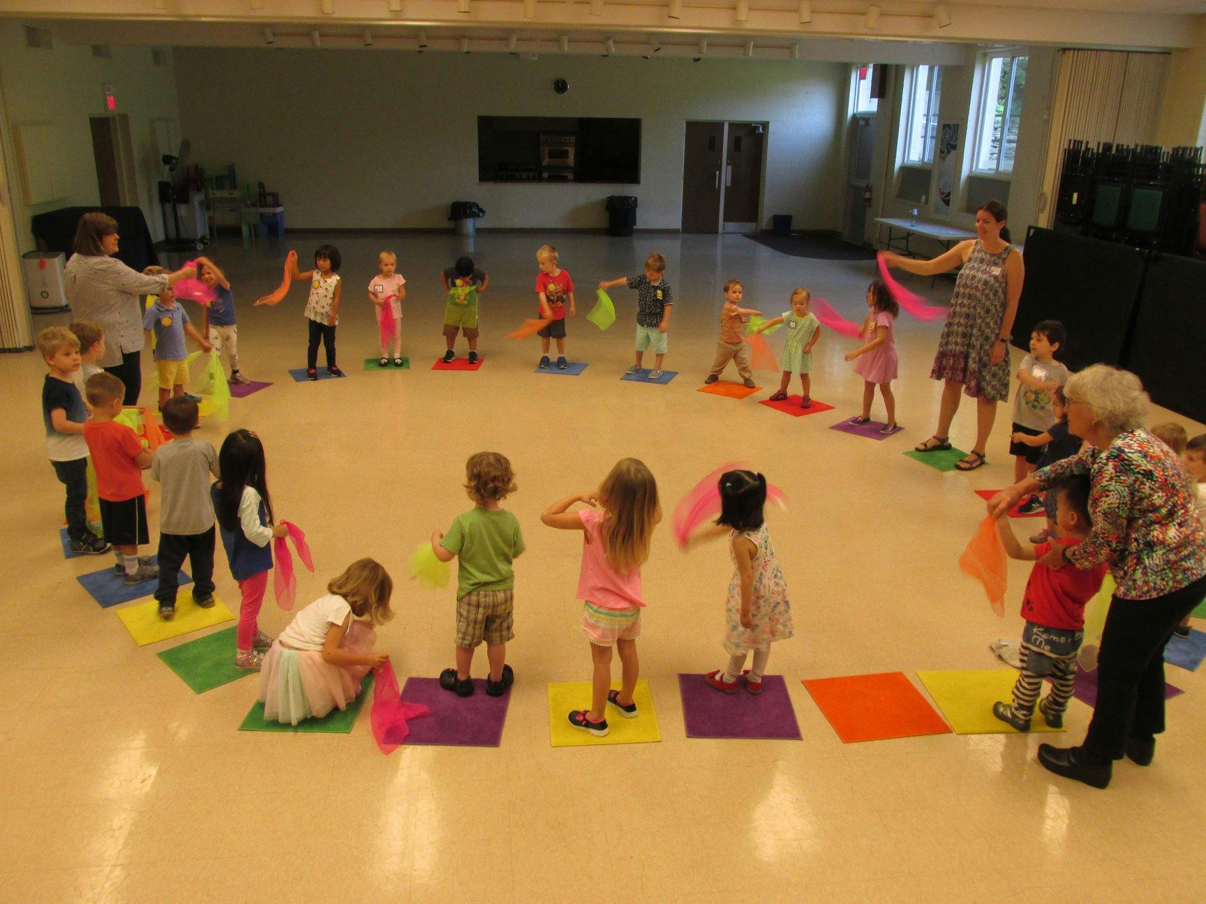 Children and adults in a circle holding colorful scarves