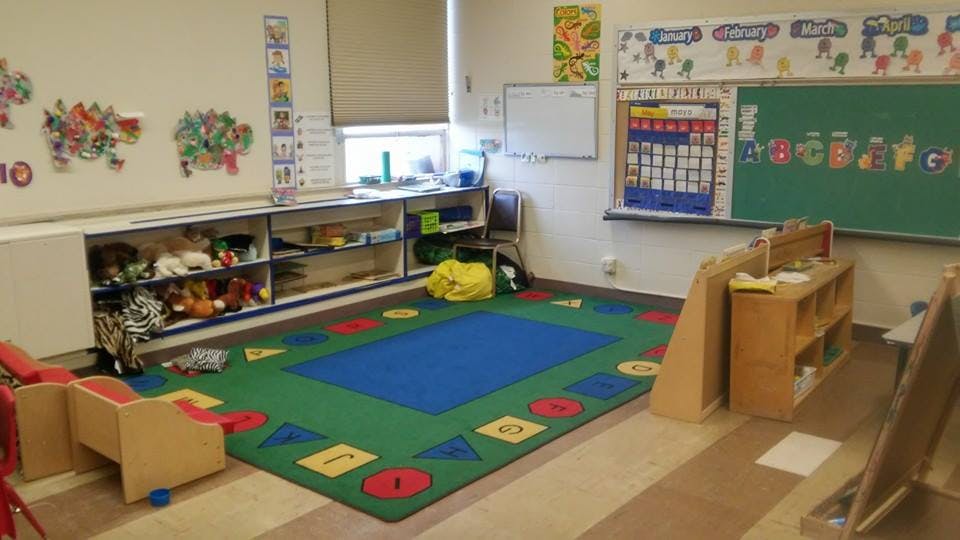 Empty classroom with a colorful rug and shelves