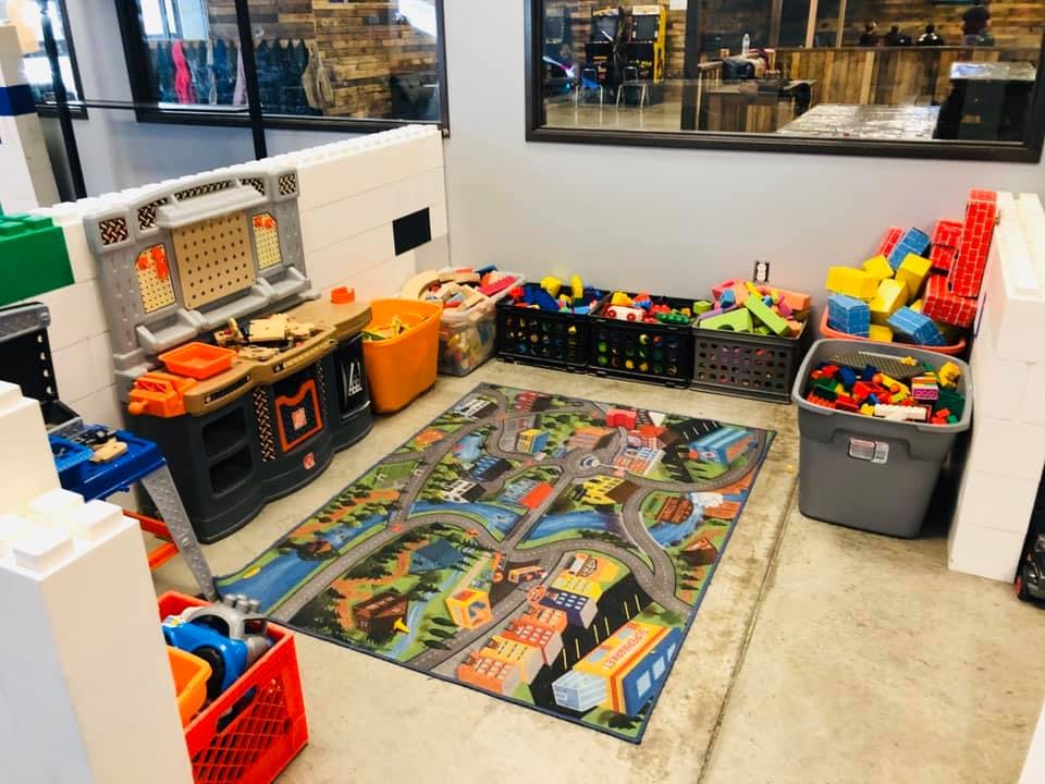 Play area with a road map rug, toy workbench, and bins of building blocks