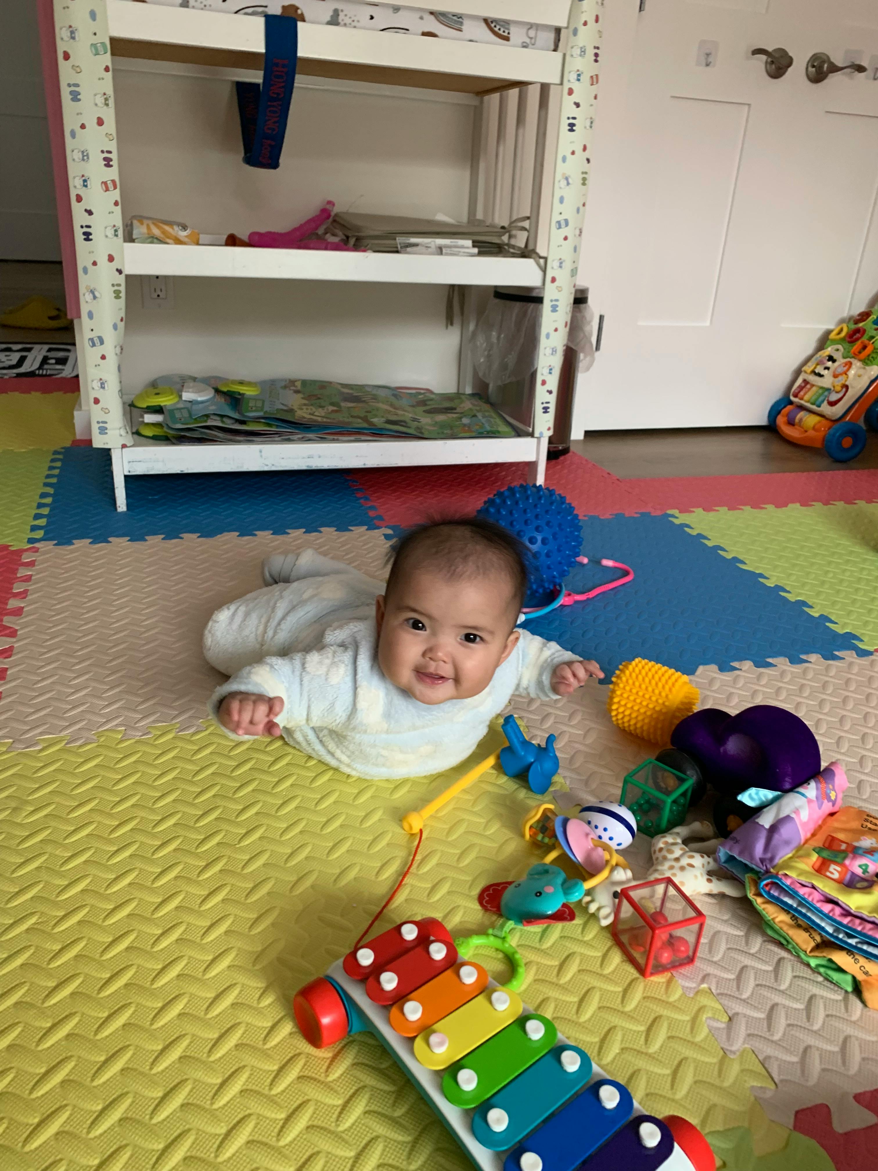 Child on stomach on a colorful playmat with toys