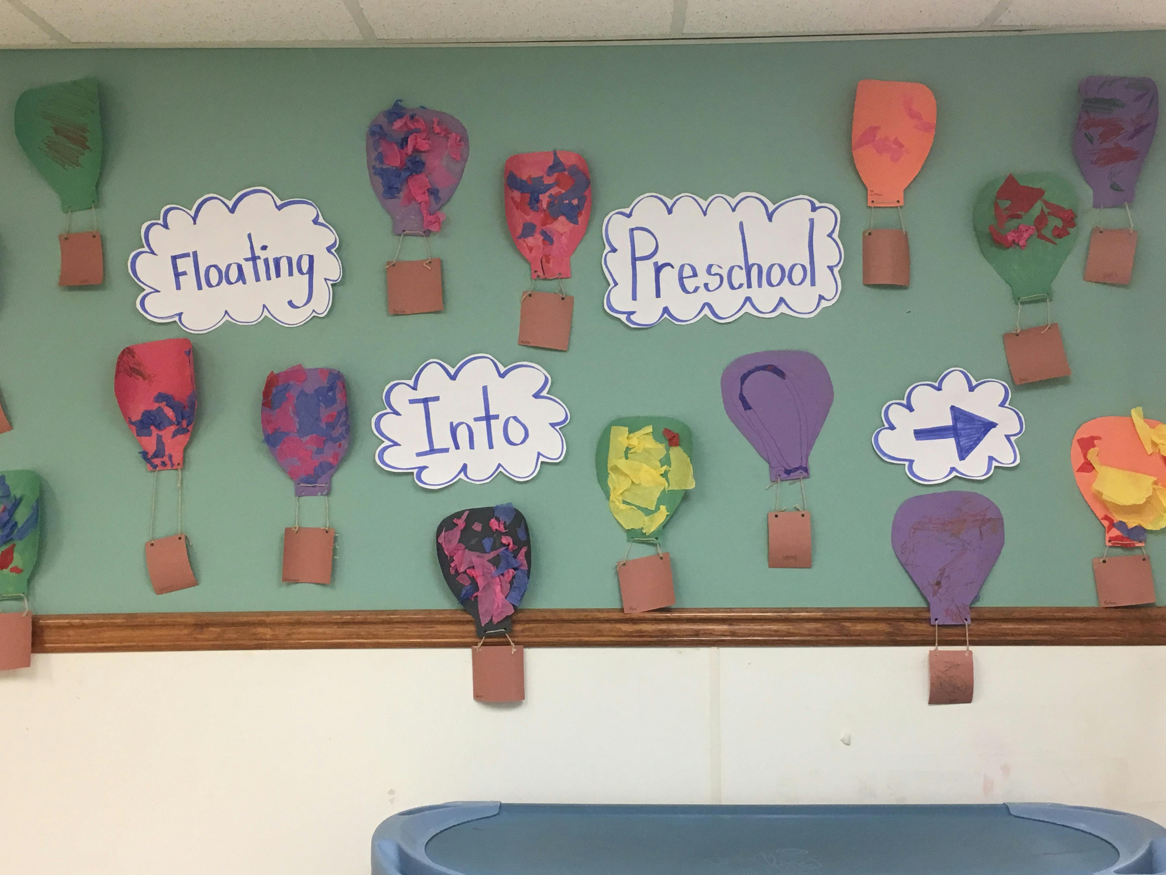 Classroom bulletin board with paper hot air balloons and "Floating Into Preschool" text