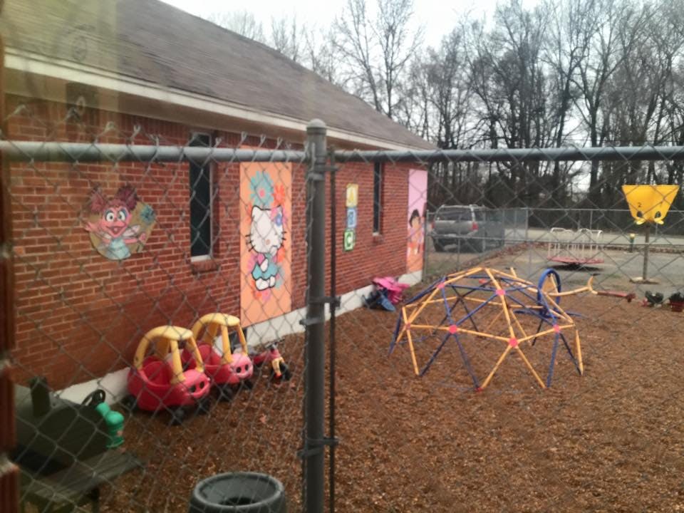 Playground with climbing dome, toy cars, and brick building with murals