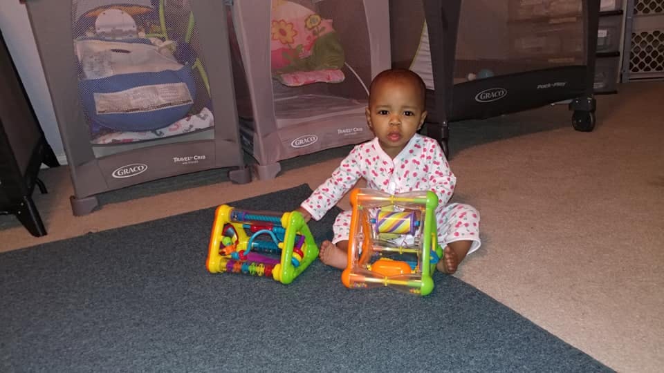 Child sitting on floor with two colorful toys