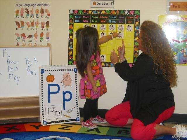 Child and person interacting with a calendar in a classroom