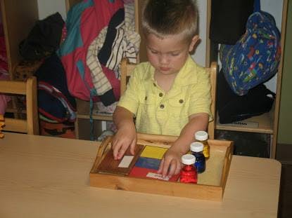 Child playing with colorful blocks and bottles on a wooden tray