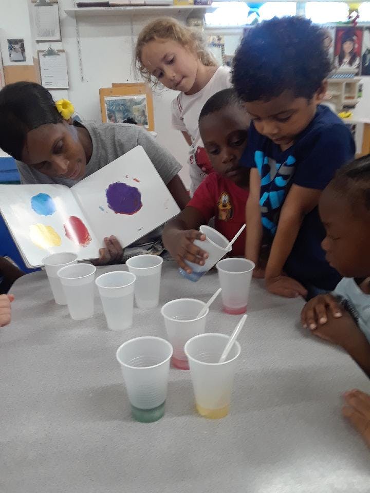 Adult and children looking at a book with colorful paint splotches