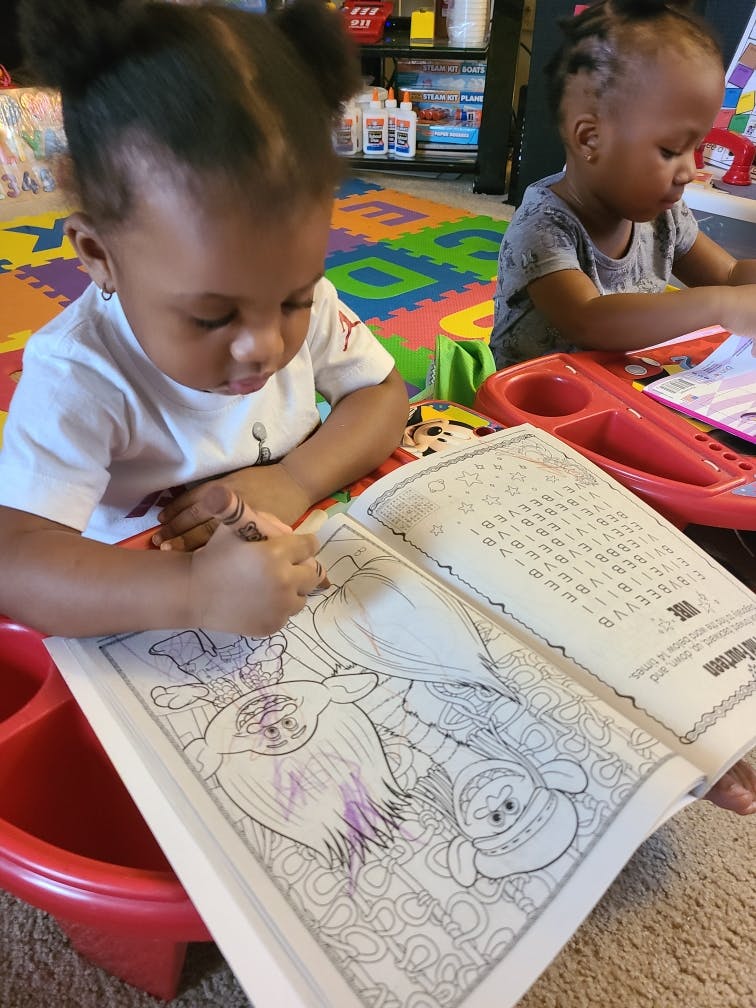 Child coloring in a book with a coloring book