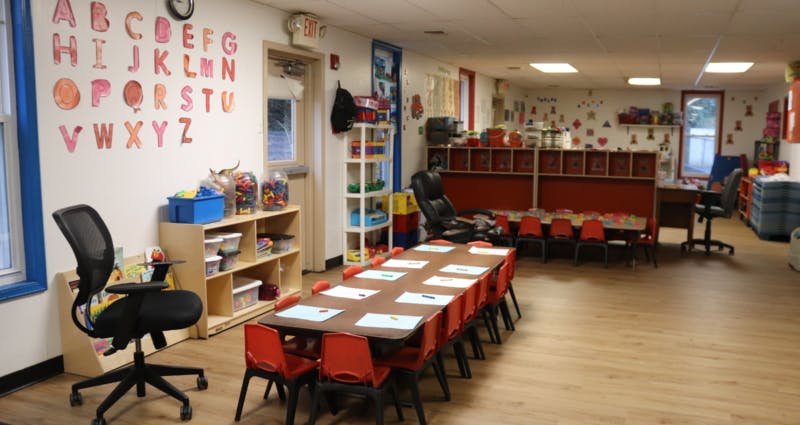 Classroom with small tables and chairs, alphabet letters on wall