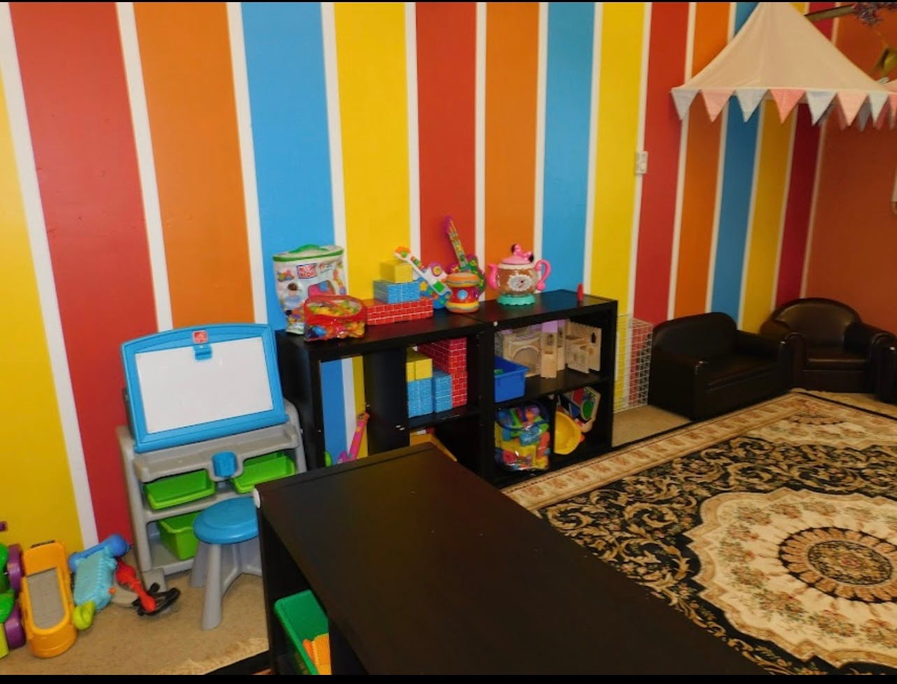 Playroom with colorful striped walls, toys, and small furniture