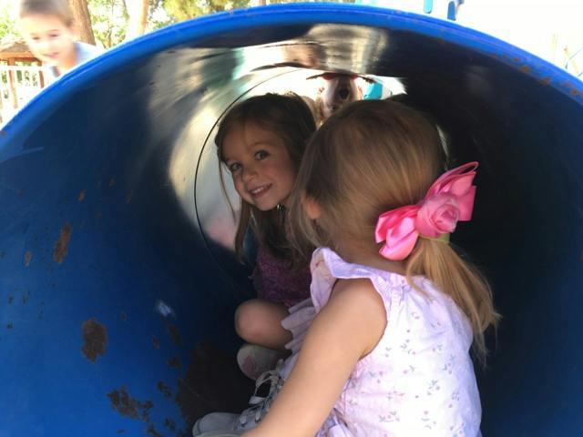 Two children in a blue tunnel on a playground