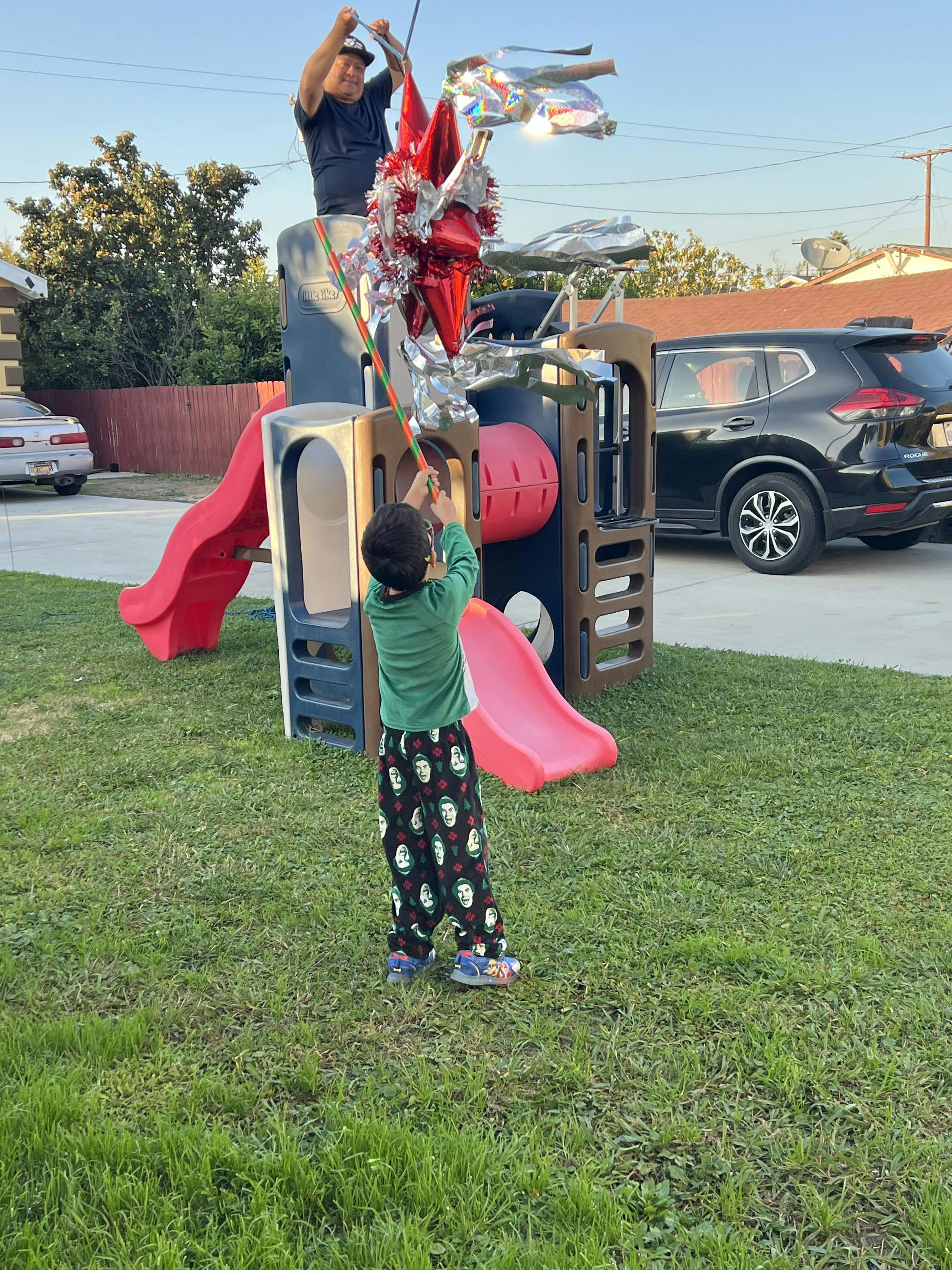 Person holding up a pinata for a child to hit with a stick